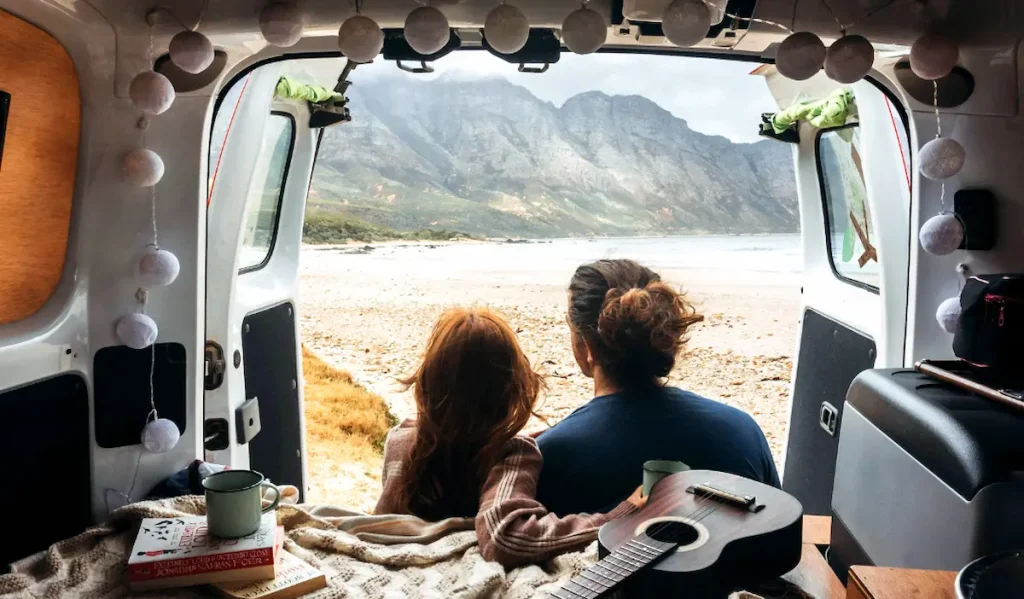 Camper all-in útitervek, lakóautó végében ül egy pár, előttük a tenger és chilleznek